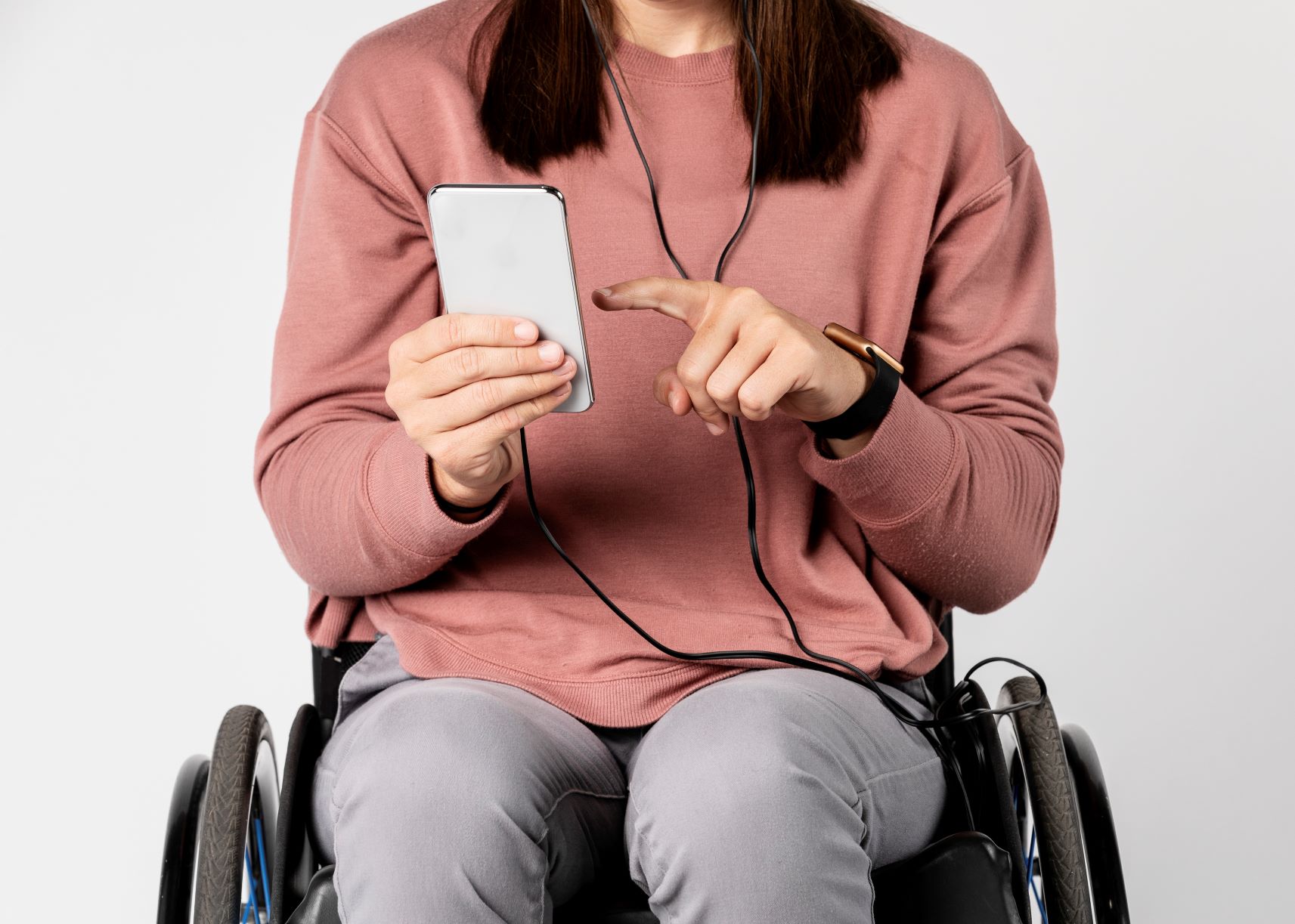 woman in a wheelchair listening to a podcast on her phone.